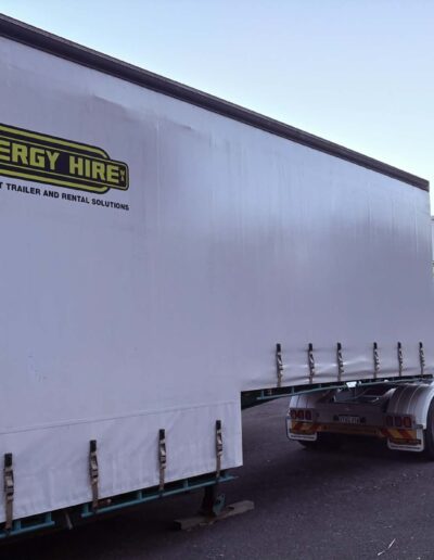 Two white curtain-side transport trailers branded “Energy Hire – Transport Trailer and Rental Solutions” parked in a lot.